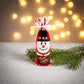 Einzelne Stoff-Flaschenhülle mit fröhlichem Schneemann-Motiv, auf glitzerndem Untergrund neben einem Tannenzweig arrangiert.